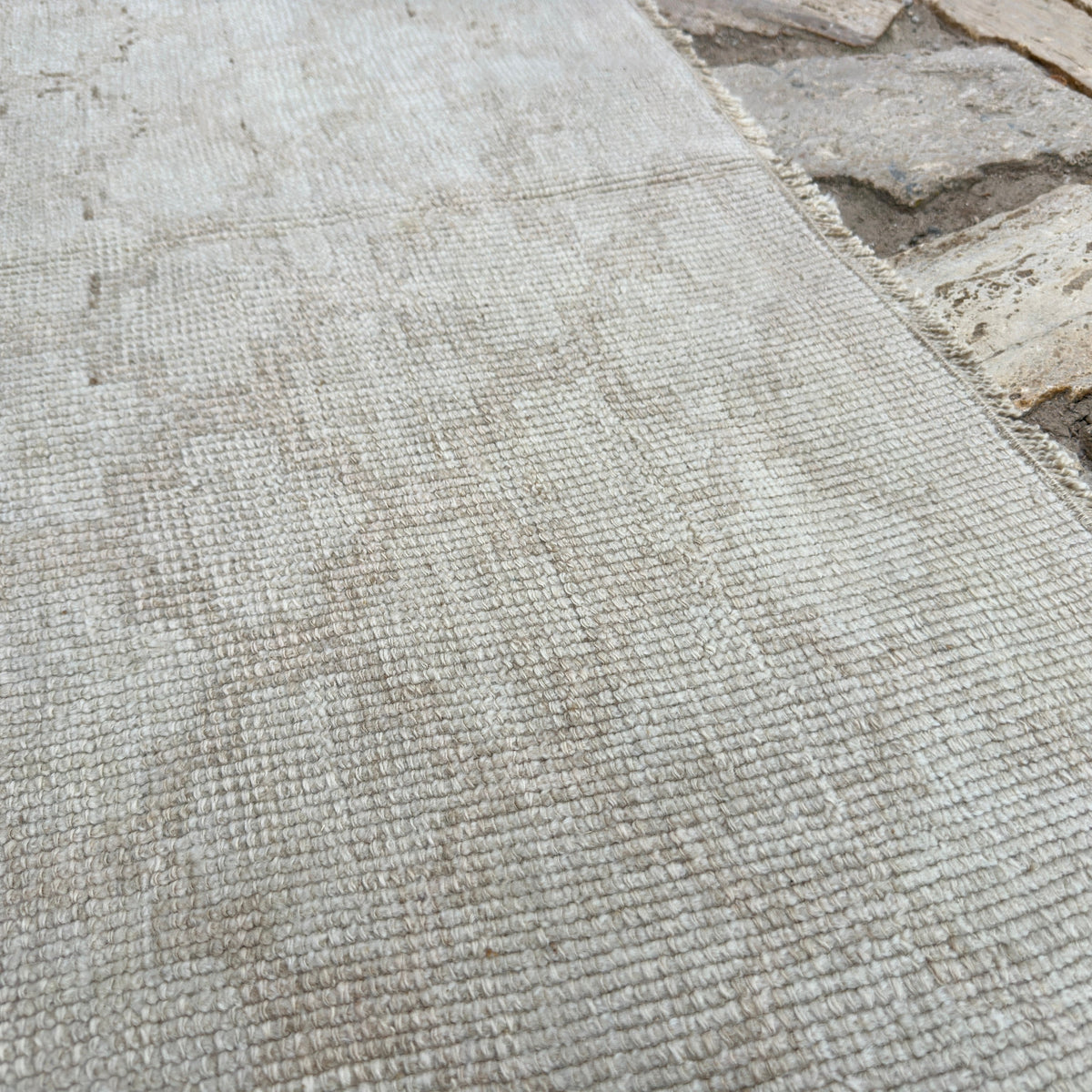 Close-up of the beige vintage Turkish distressed rug showing geometric details, hand-knotted weave, wool and cotton and low pile.