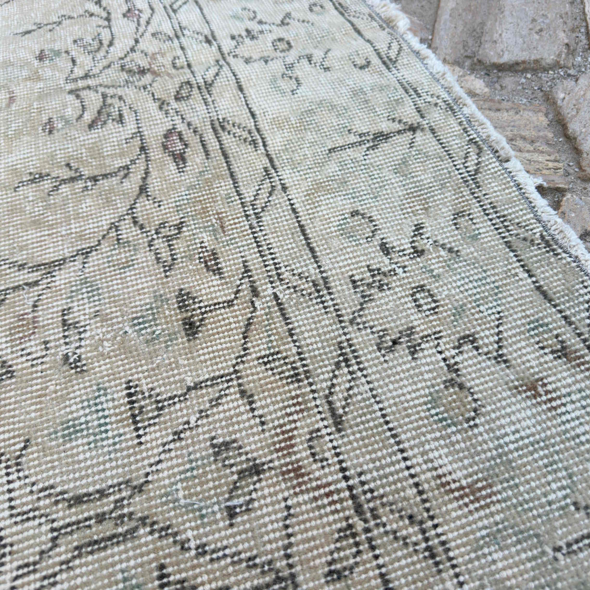 Close-up of the beige vintage Turkish distressed rug showing neutral details, hand-knotted weave, wool and cotton and low pile.