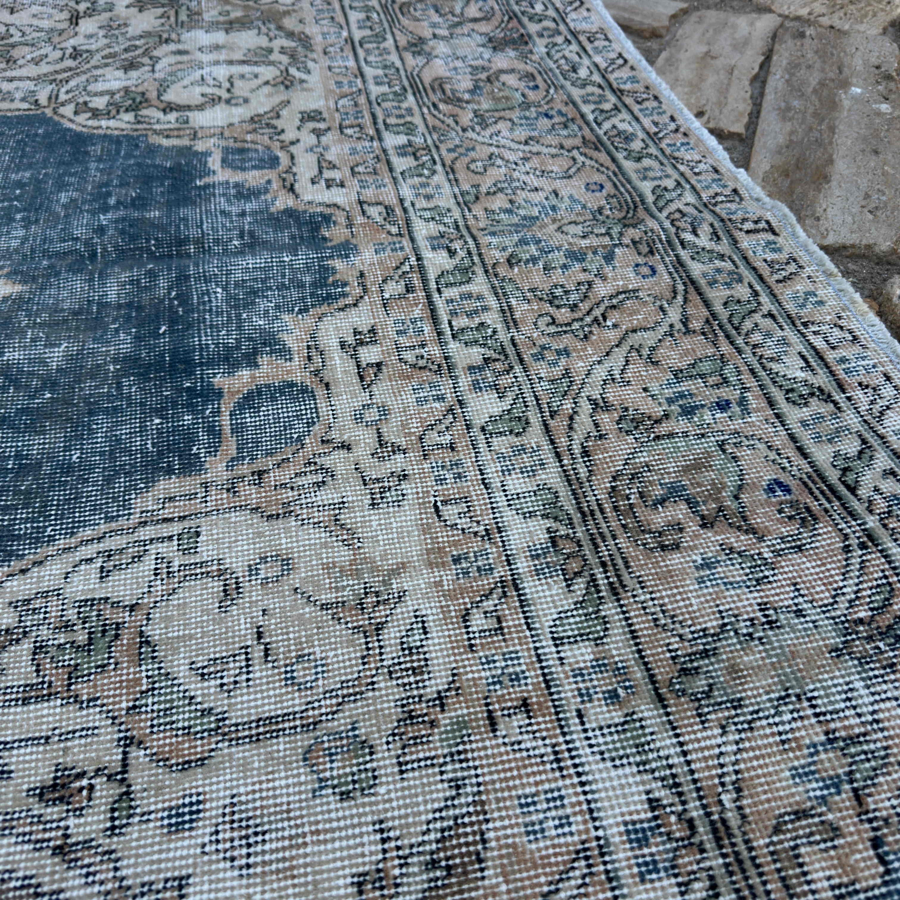 Close-up of the blue vintage Turkish distressed rug showing medallion details, hand-knotted weave, wool and cotton and low pile.