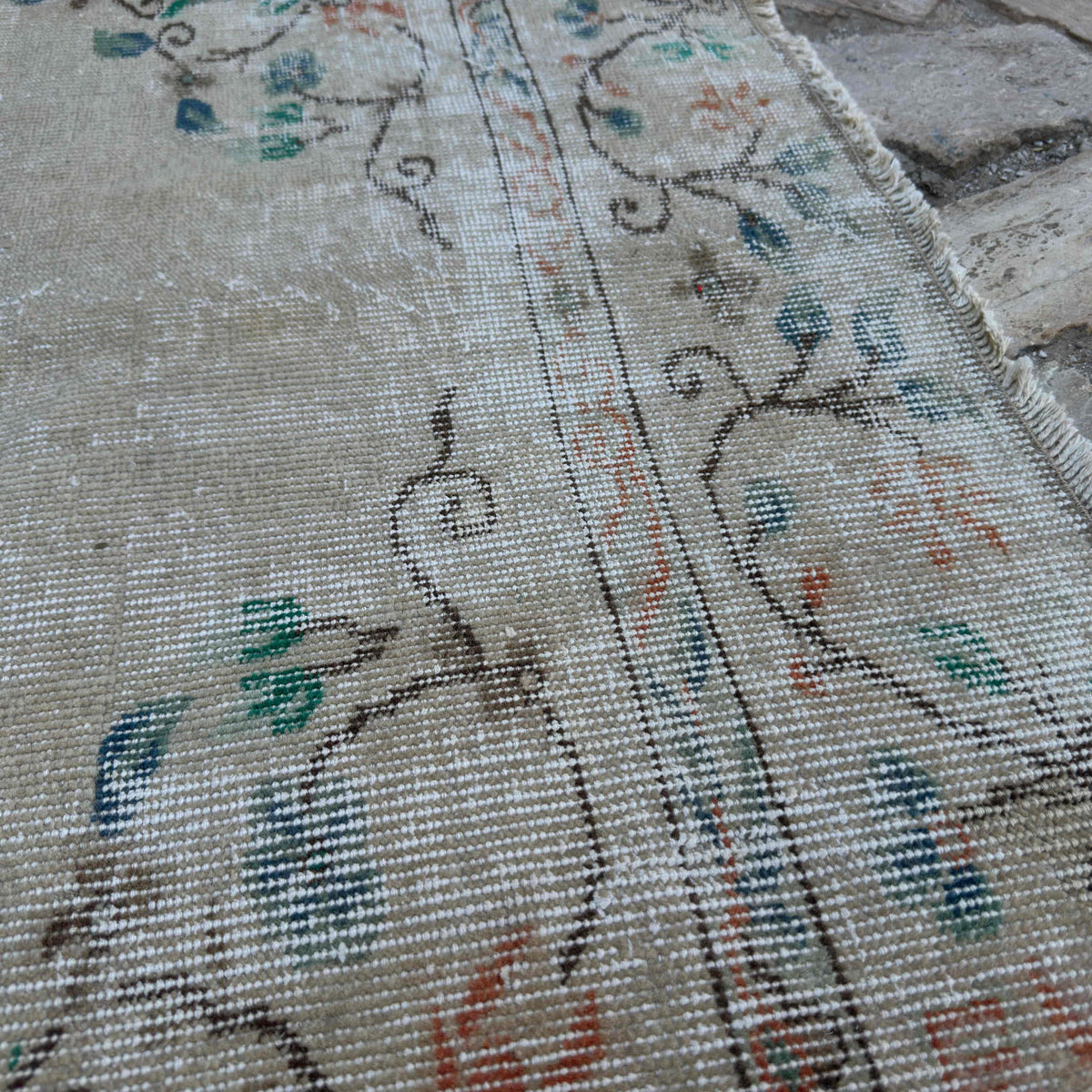 Close-up of the beige vintage Turkish distressed rug showing medallion details, hand-knotted weave, wool and cotton and low pile.