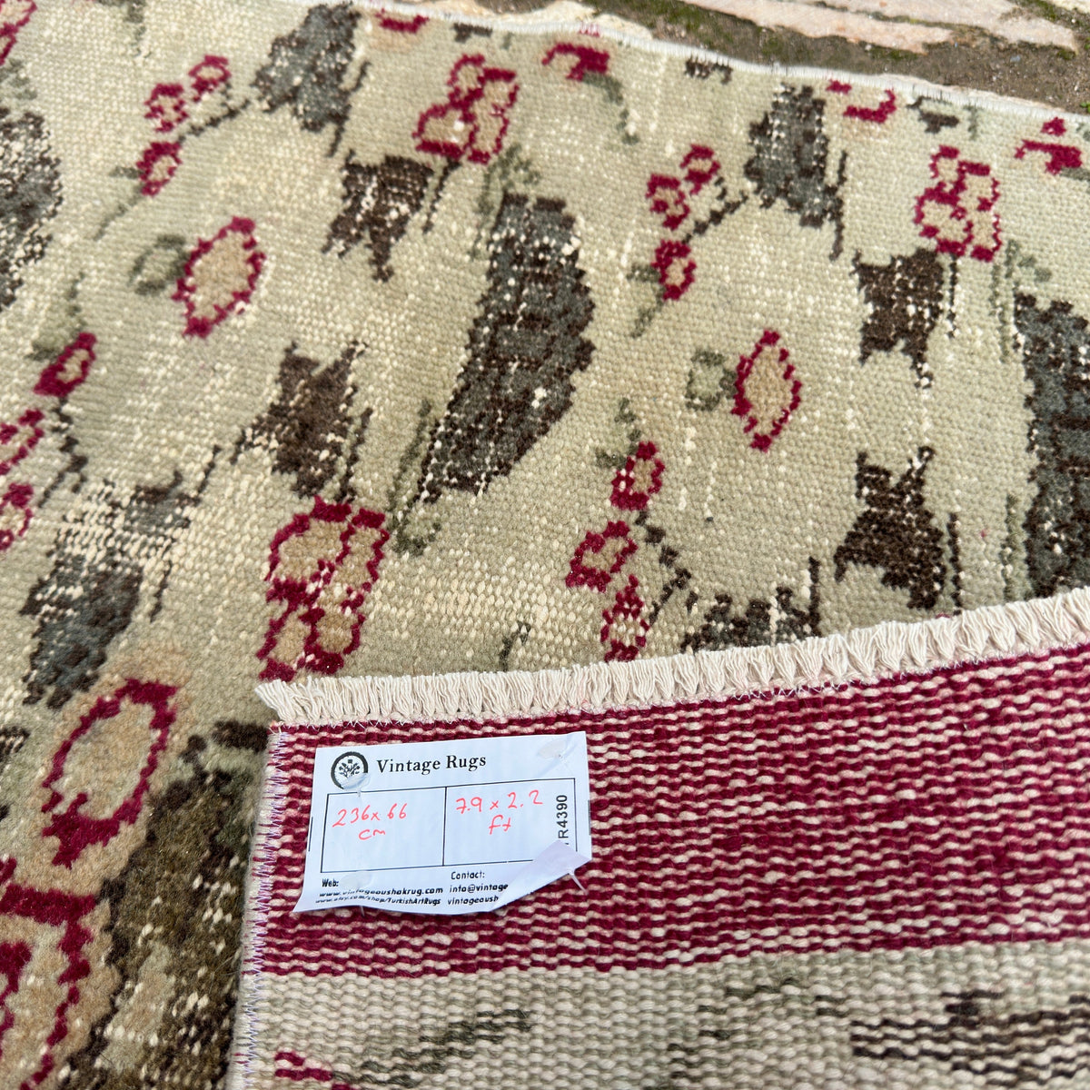 Close-up of the green vintage Turkish distressed runner rug showing floral details, hand-knotted weave, wool and cotton and low pile.