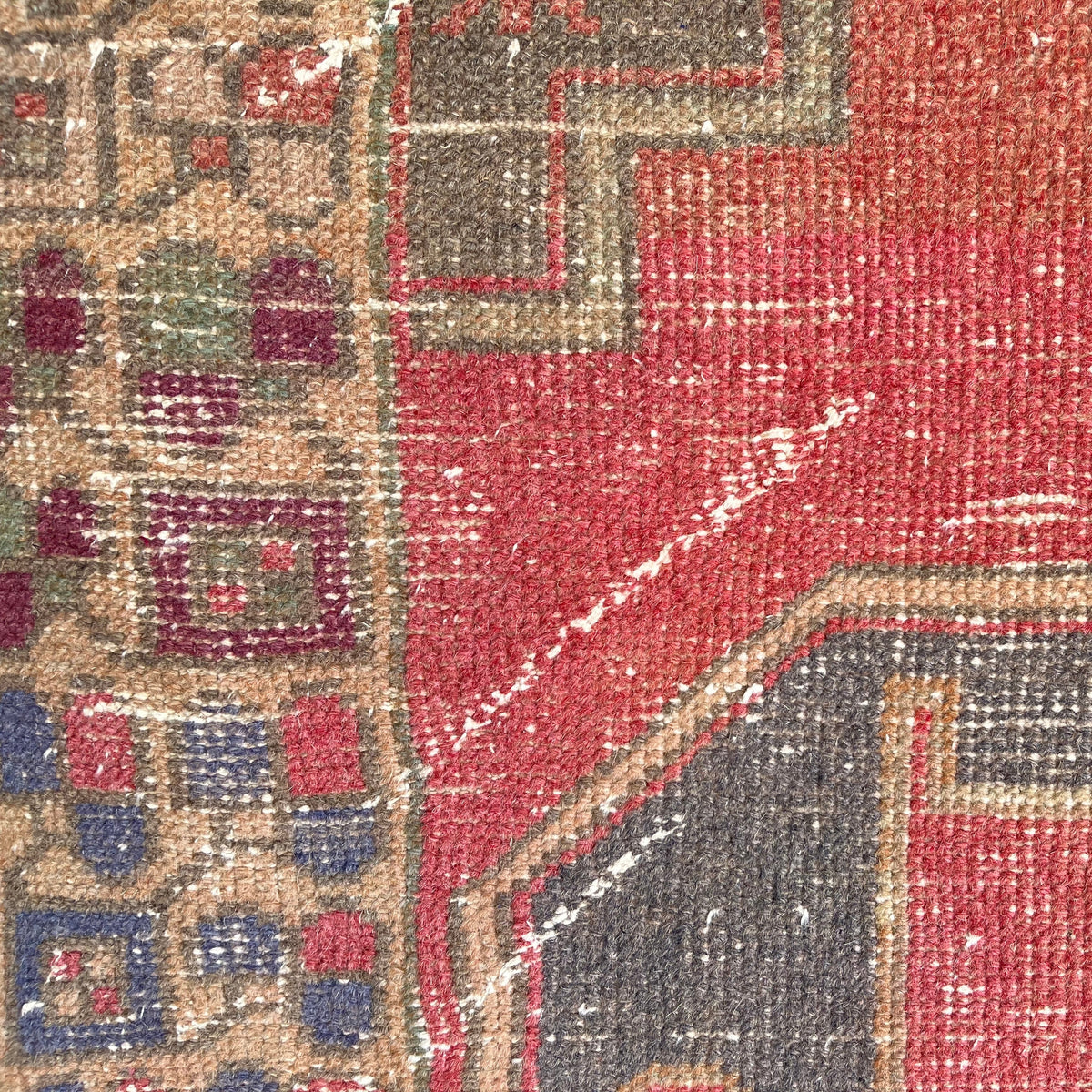 Close-up of the red vintage Turkish distressed runner rug showing traditional details, hand-knotted weave, wool and cotton and low pile.