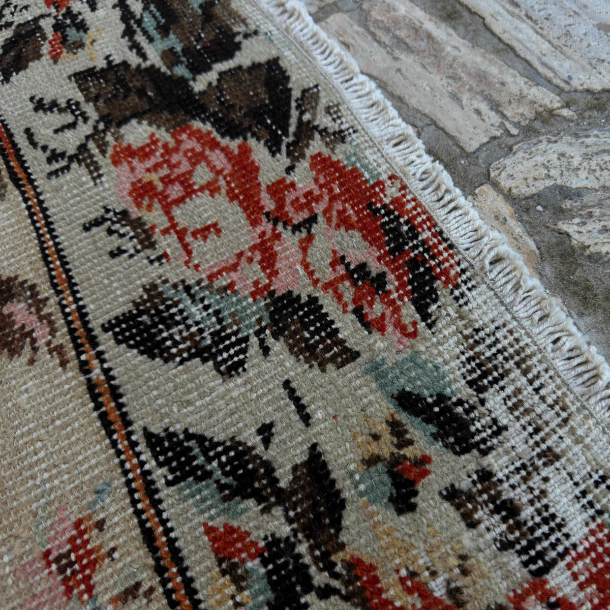 Close-up of the beige vintage Turkish floral rug showing floral details, hand-knotted weave, wool and cotton and low pile.