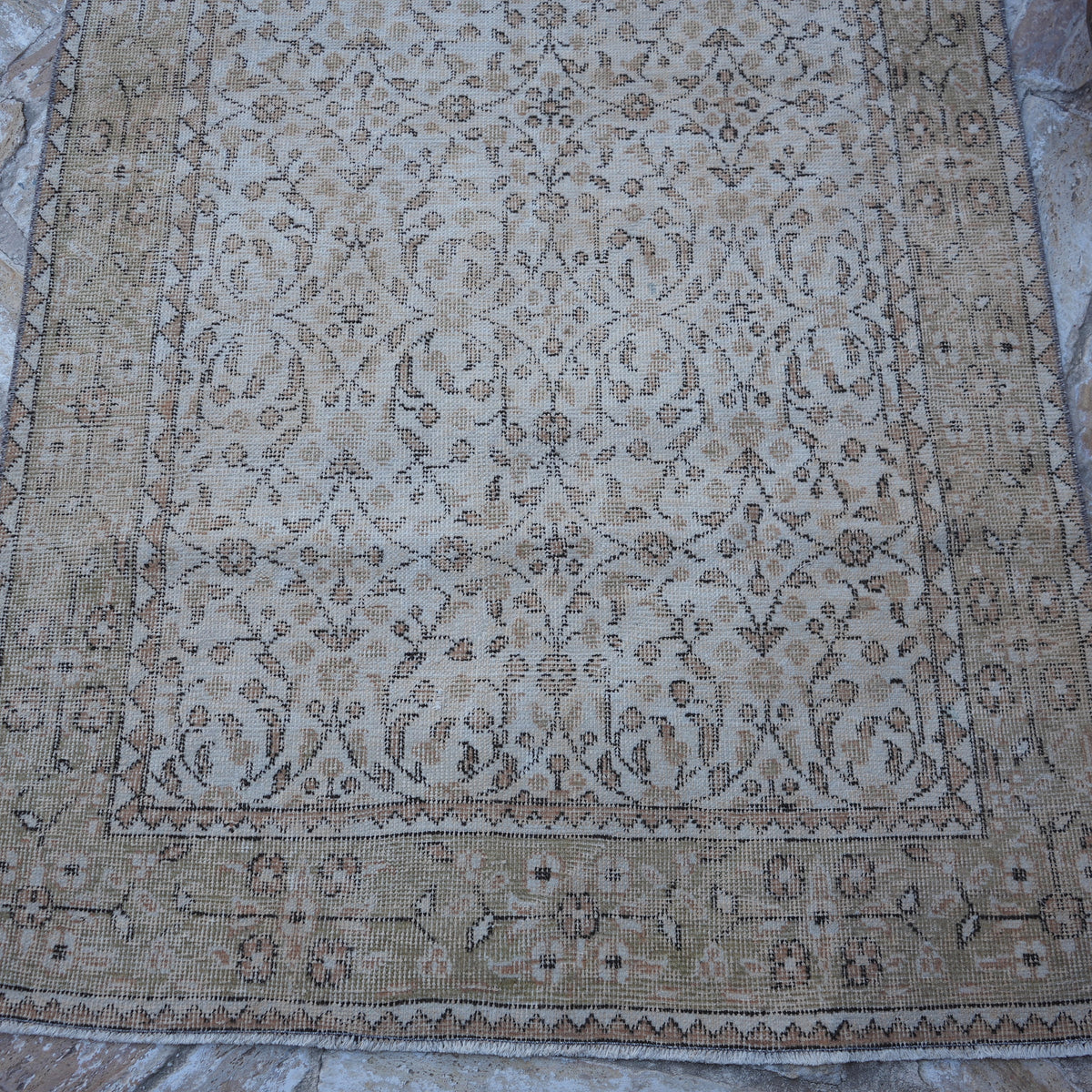Close-up of the beige vintage Turkish floral rug showing floral details, hand-knotted weave, wool and cotton and low pile.