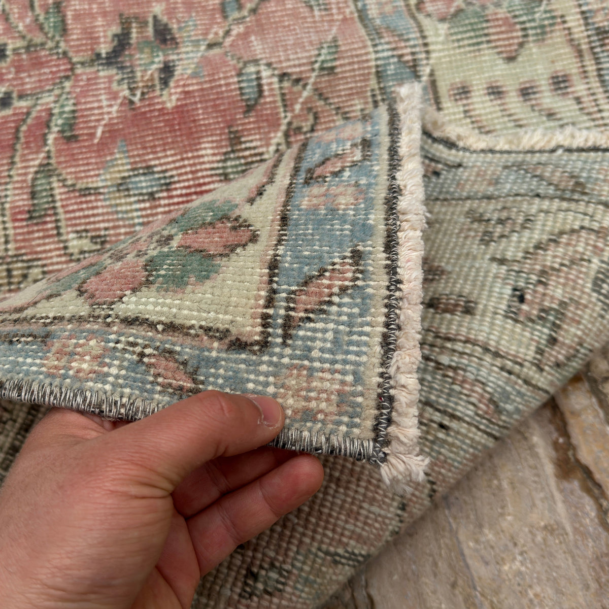Close-up of the pink vintage Turkish floral rug showing floral details, hand-knotted weave, wool and cotton and low pile.