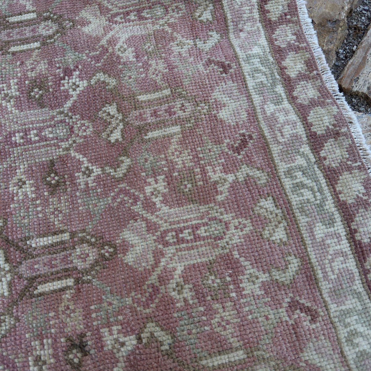 Close-up of the pink vintage Turkish floral rug showing floral details, hand-knotted weave, wool and cotton and low pile.