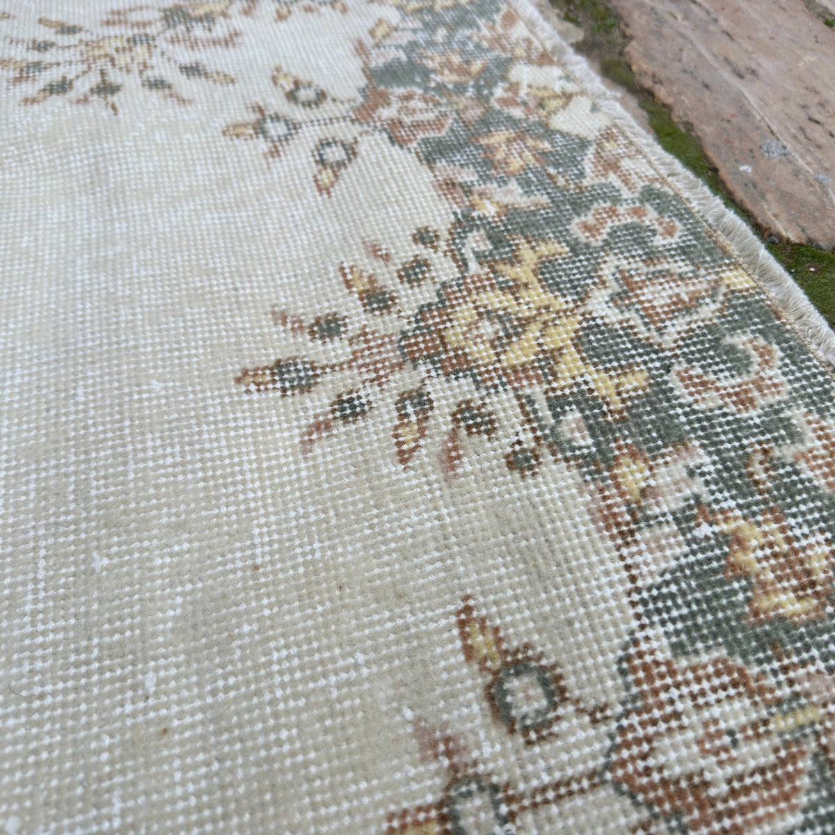Close-up of the pale green vintage Turkish geometric rug showing medallion details, hand-knotted weave, wool and cotton and low pile.