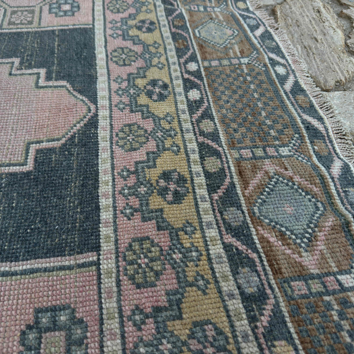 Close-up of the pink vintage Turkish geometric rug showing traditional details, hand-knotted weave, wool and cotton and low pile.