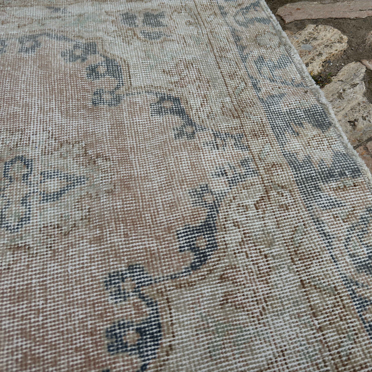 Close-up of the pale pink vintage Turkish isparta rug showing medallion details, hand-knotted weave, wool and cotton and low pile.