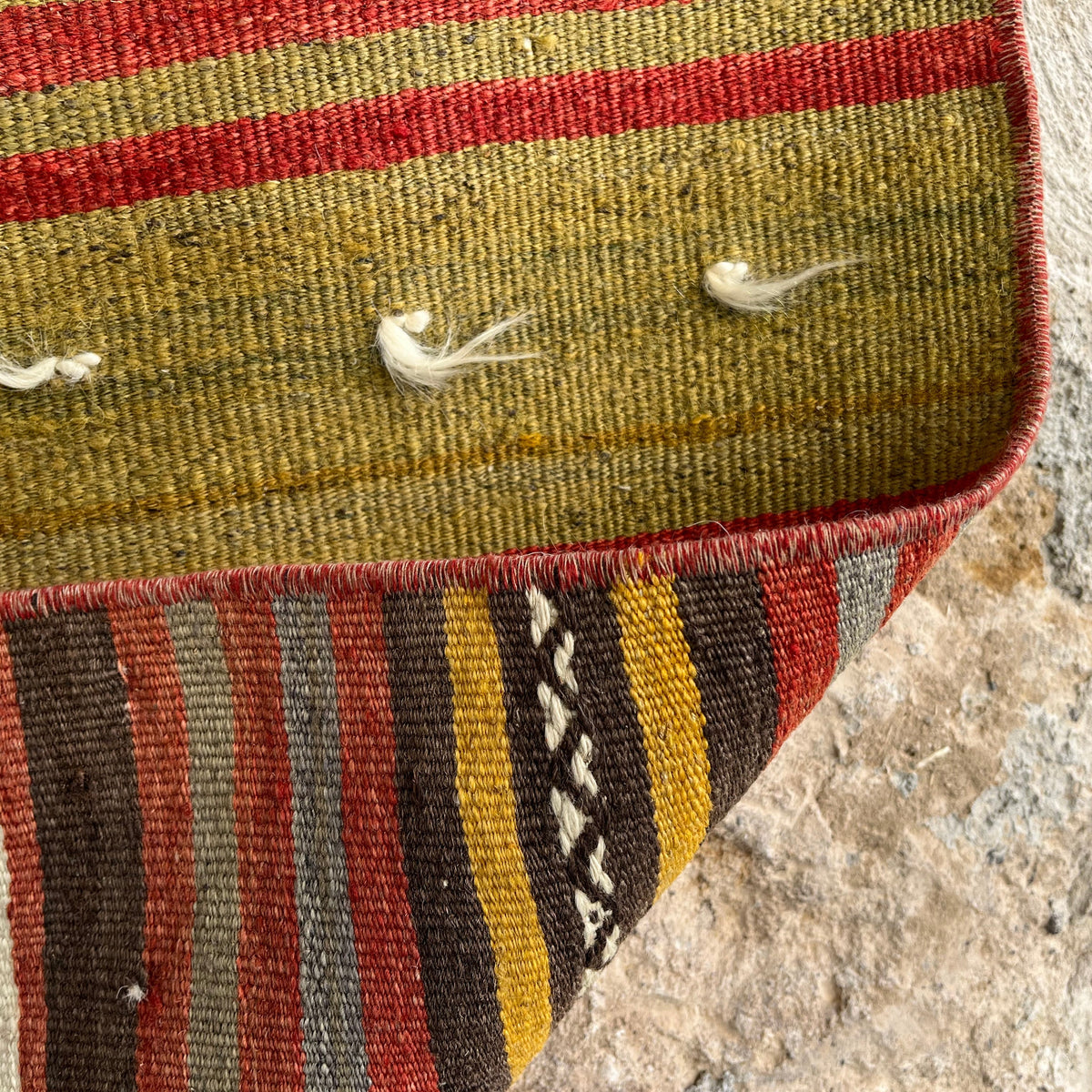 Close-up of the red vintage Turkish kilim rug showing striped details, flatweave construction, wool and cotton and low pile.
