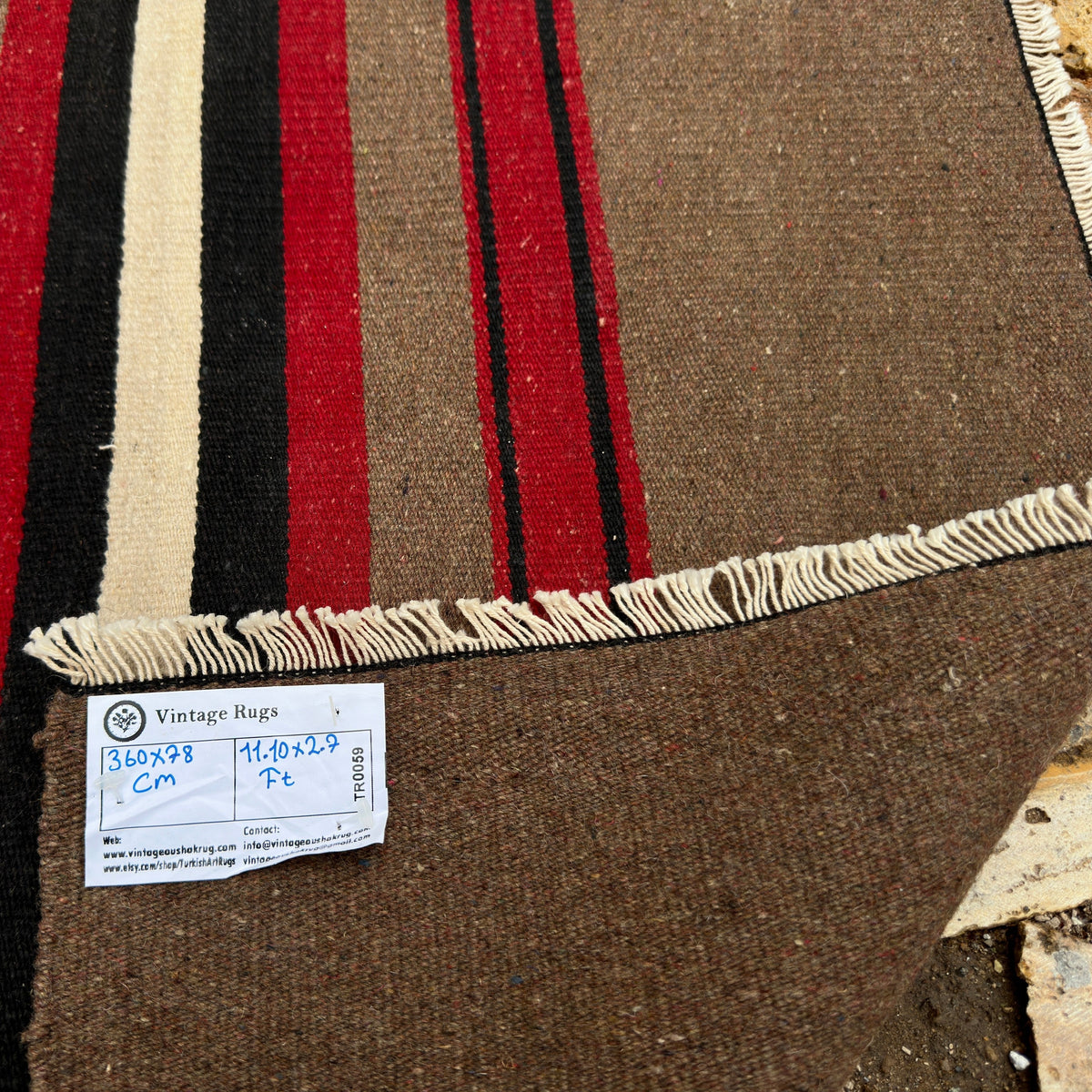 Close-up of the brown vintage Turkish kilim runner rug showing striped details, flatweave construction, wool and cotton and low pile.