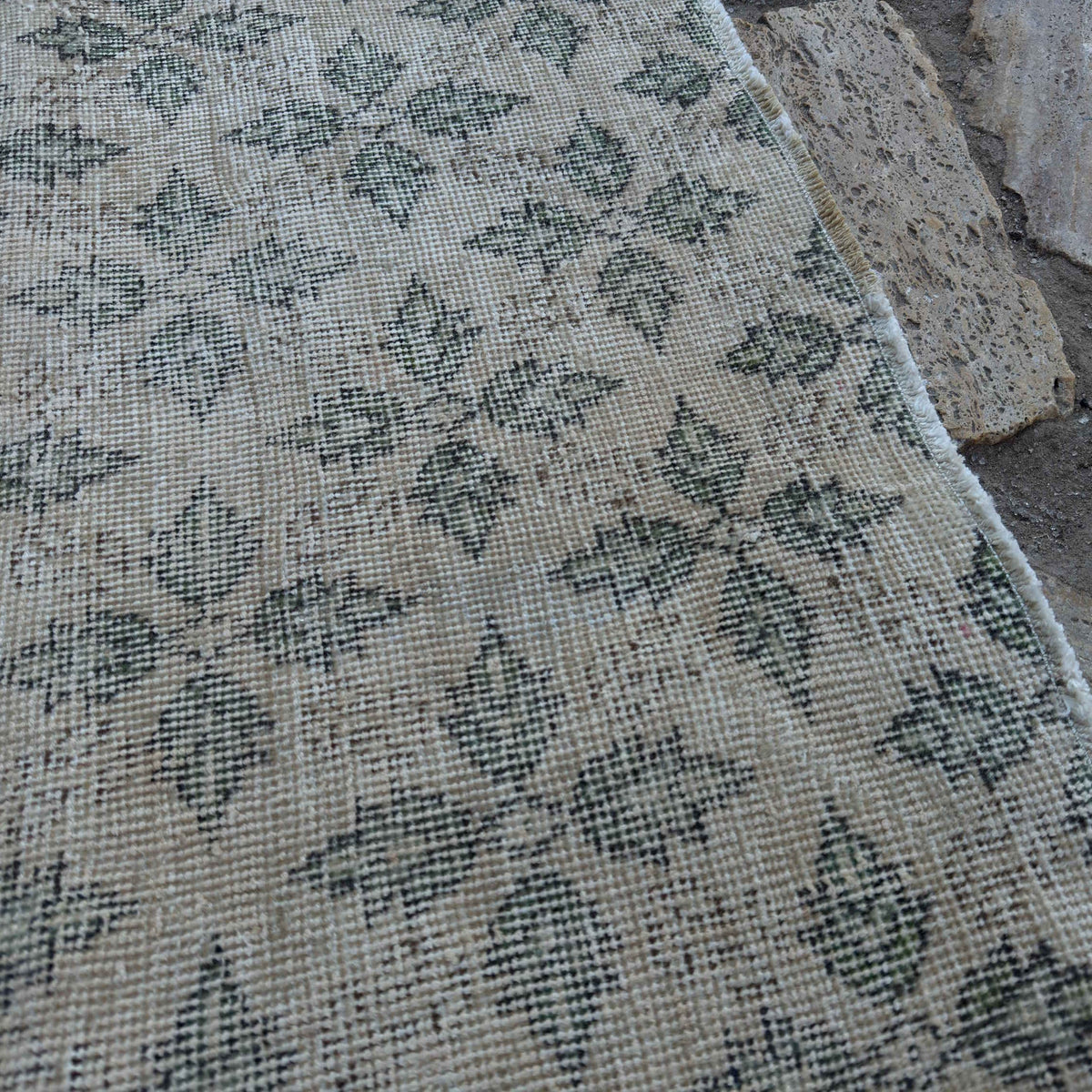 Close-up of the beige vintage Turkish low pile rug showing floral details, hand-knotted weave, wool and cotton and low pile.