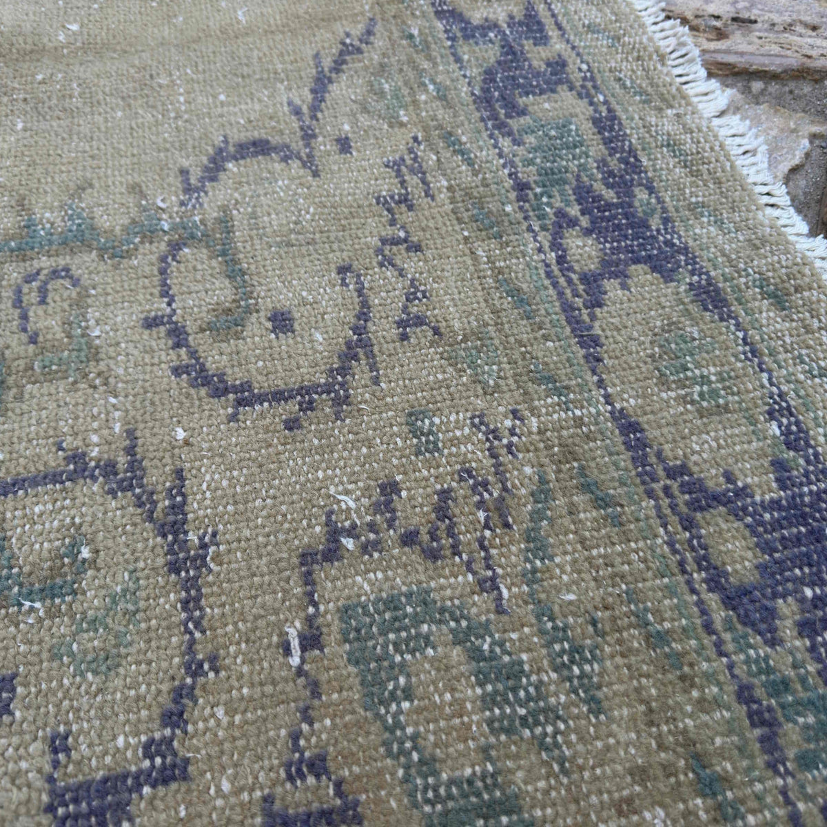 Close-up of the blue vintage Turkish medallion rug showing neutral details, hand-knotted weave, wool and cotton and low pile.