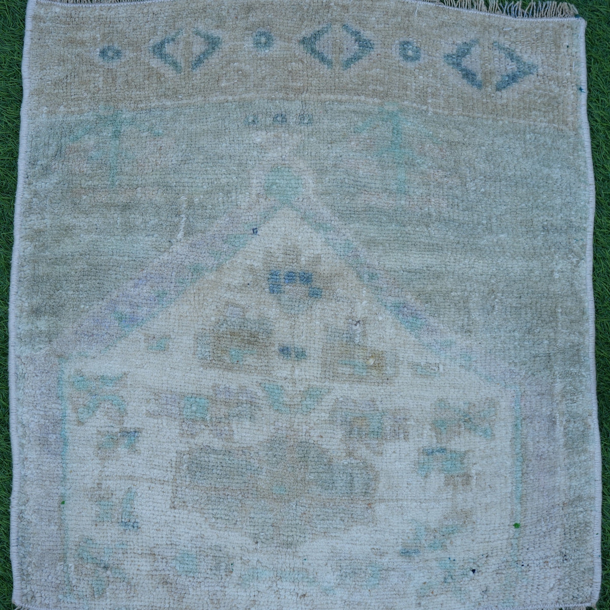 Close-up of the beige vintage Turkish mini rug showing traditional details, hand-knotted weave, wool and cotton and low pile.