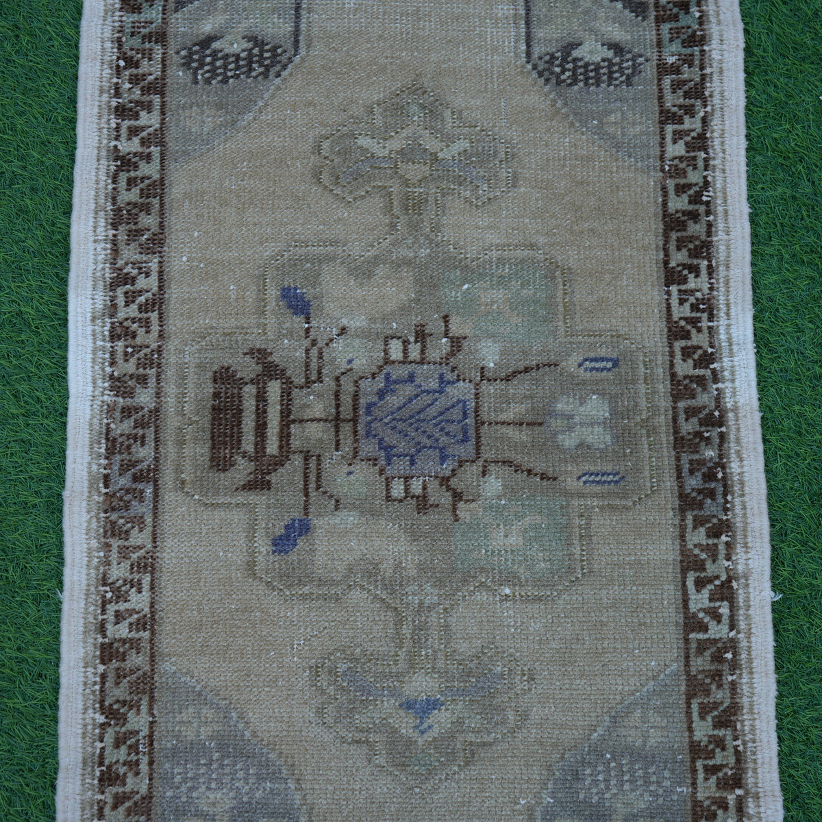 Close-up of the beige vintage Turkish mini rug showing traditional details, hand-knotted weave, wool and cotton and low pile.