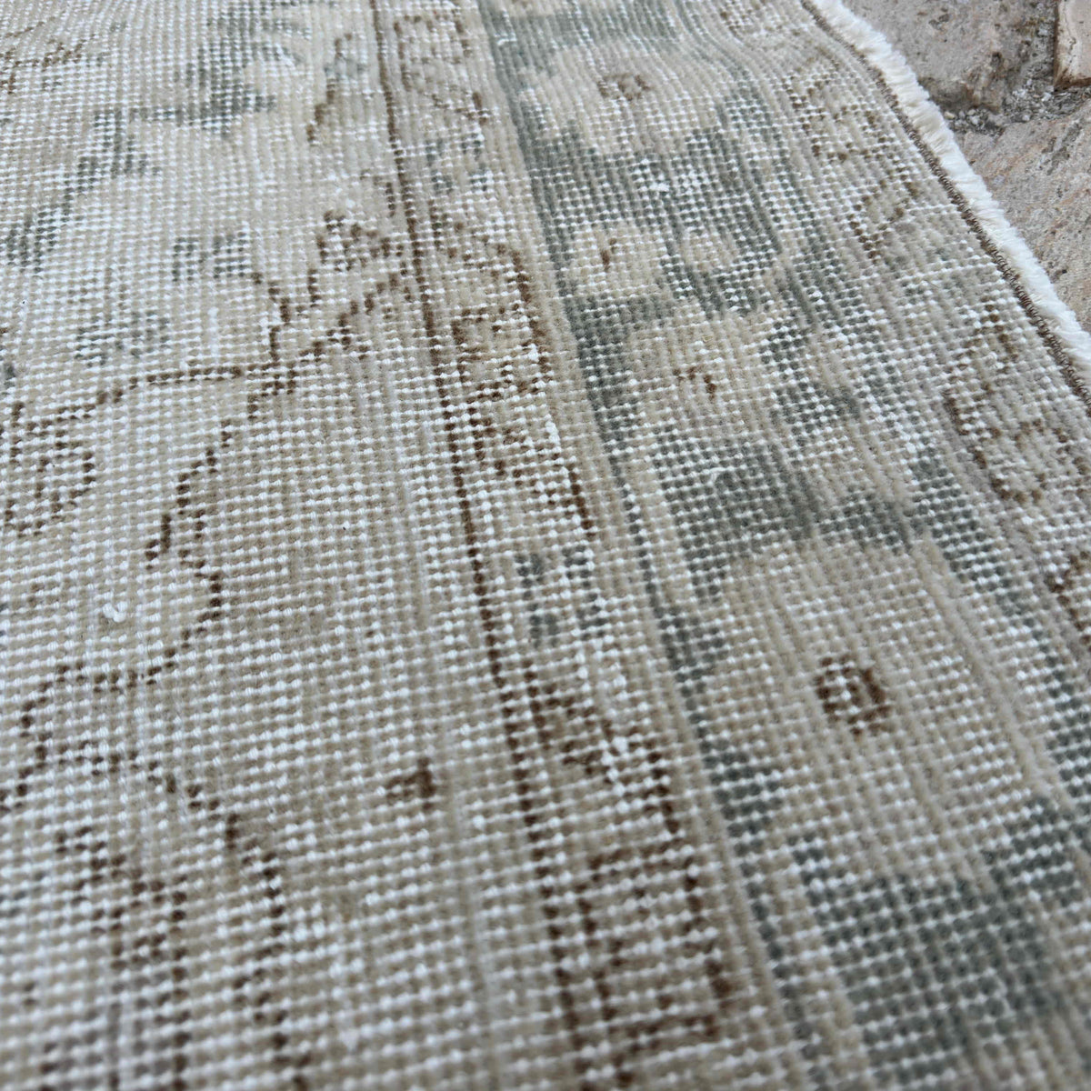 Close-up of the beige vintage Turkish muted rug showing neutral details, hand-knotted weave, wool and cotton and low pile.