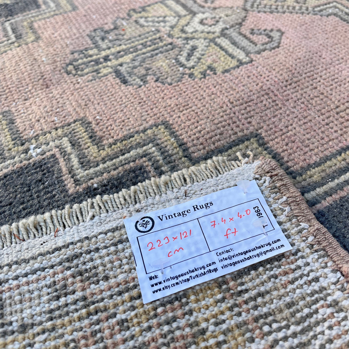 Close-up of the pink vintage Turkish oriental rug showing geometric details, hand-knotted weave, wool and cotton and low pile.