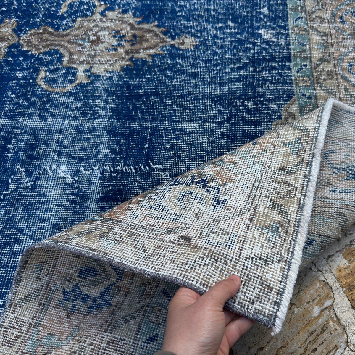 Close-up of the blue vintage Turkish oriental rug showing geometric details, hand-knotted weave, wool and cotton and low pile.