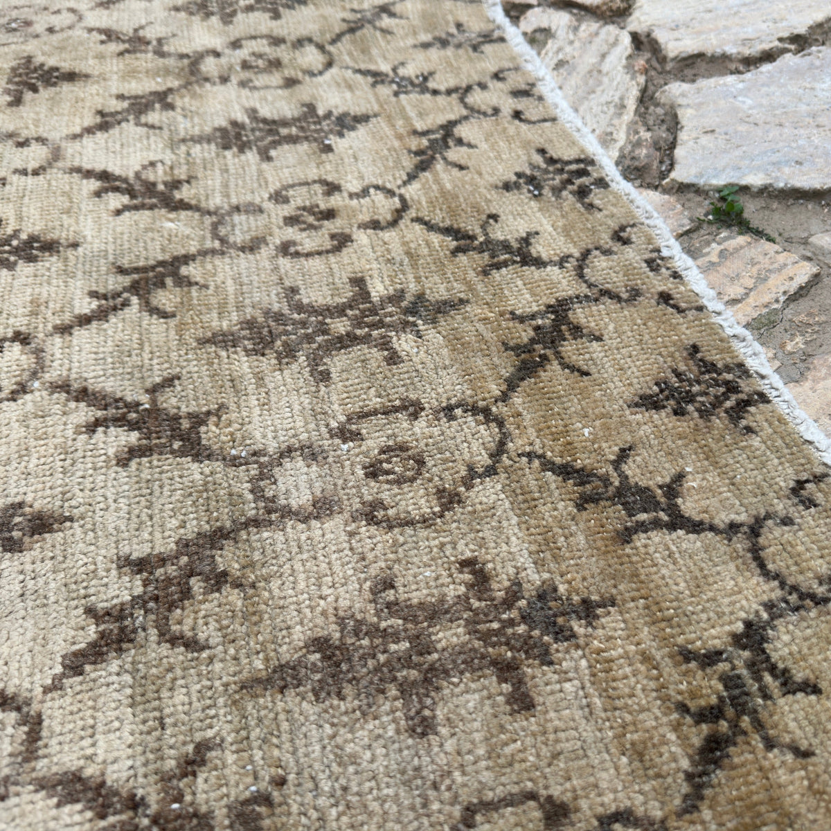 Close-up of the beige vintage Turkish oushak rug showing floral details, hand-knotted weave, wool and cotton and low pile.