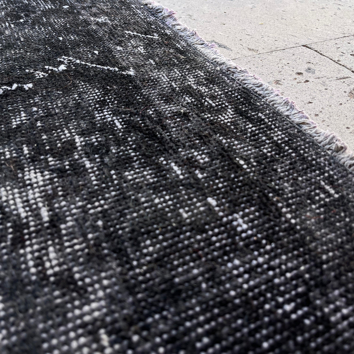 Close-up of the black vintage Turkish overdyed rug showing overdyed details, hand-knotted weave, wool and cotton and low pile.