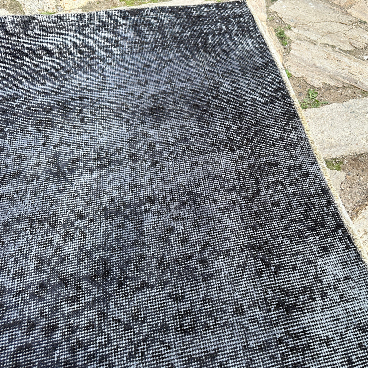 Close-up of the black vintage Turkish overdyed rug, hand-knotted weave, wool and cotton and low pile.