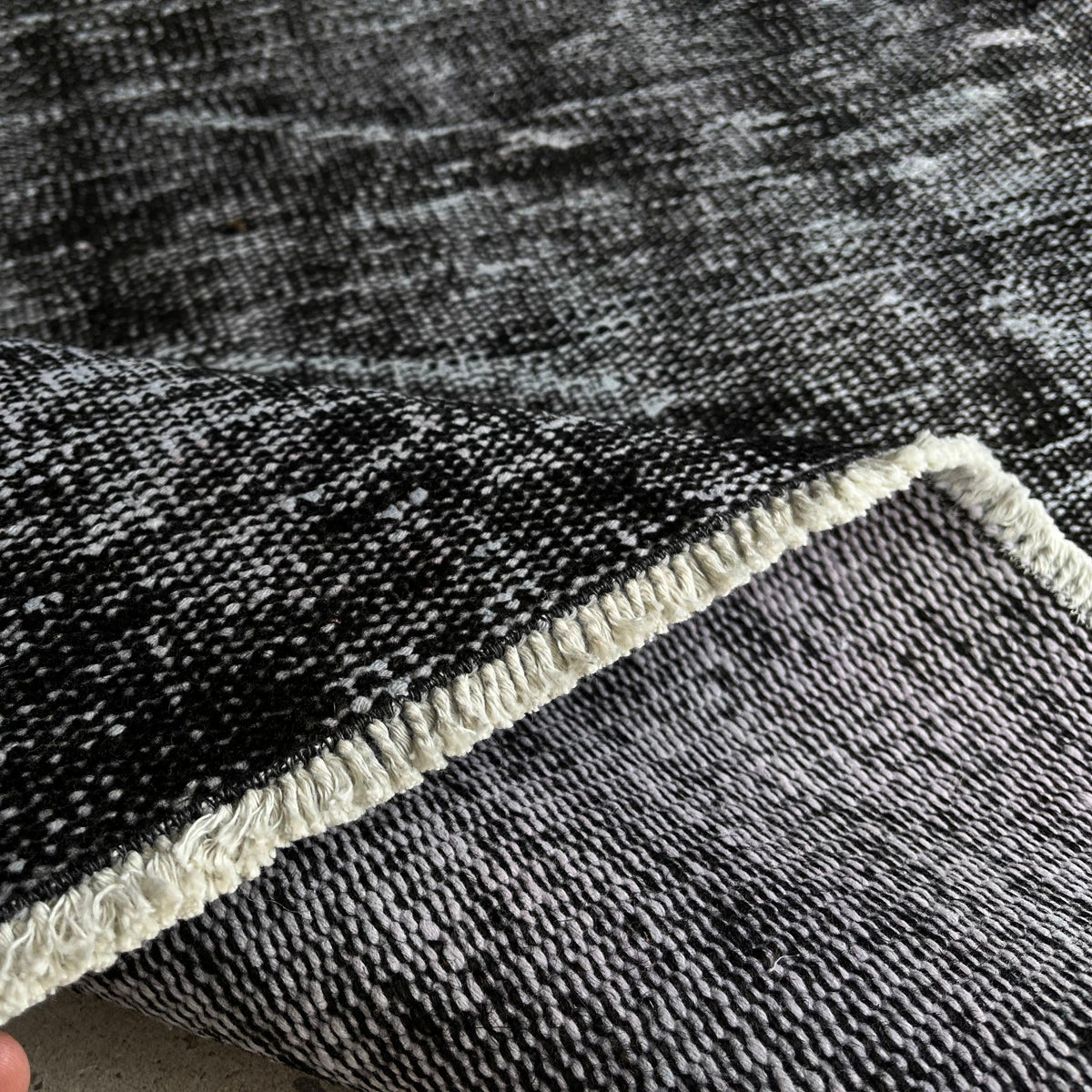 Close-up of the black vintage Turkish overdyed rug showing overdyed details, hand-knotted weave, wool and cotton and low pile.