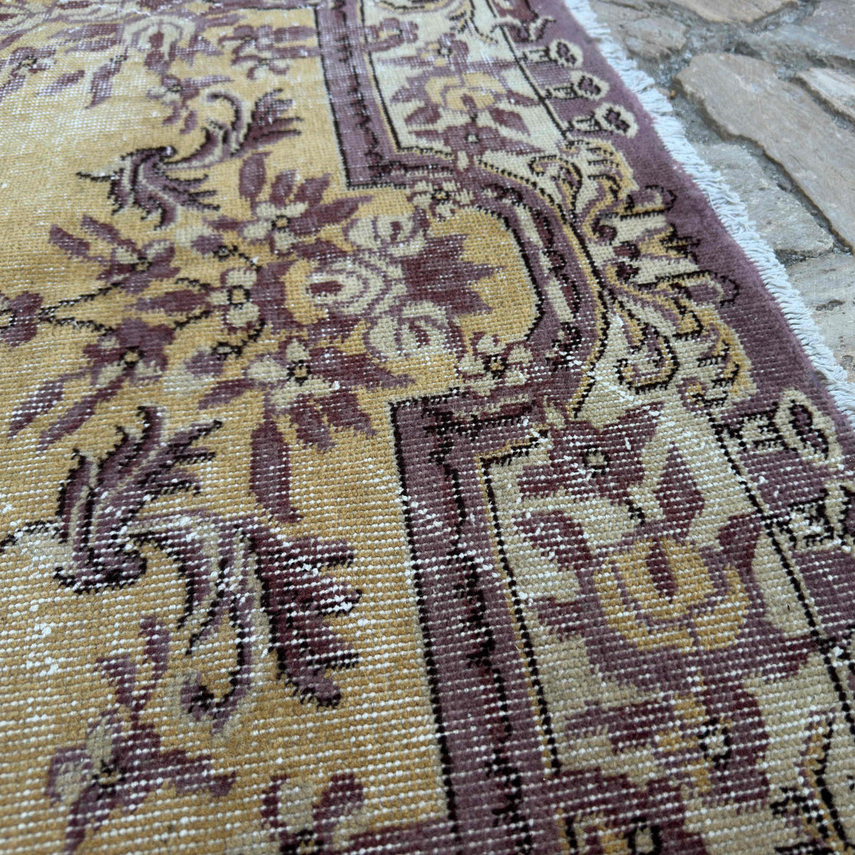 Close-up of the yellow vintage Turkish persian rug showing medallion details, hand-knotted weave, wool and cotton and low pile.