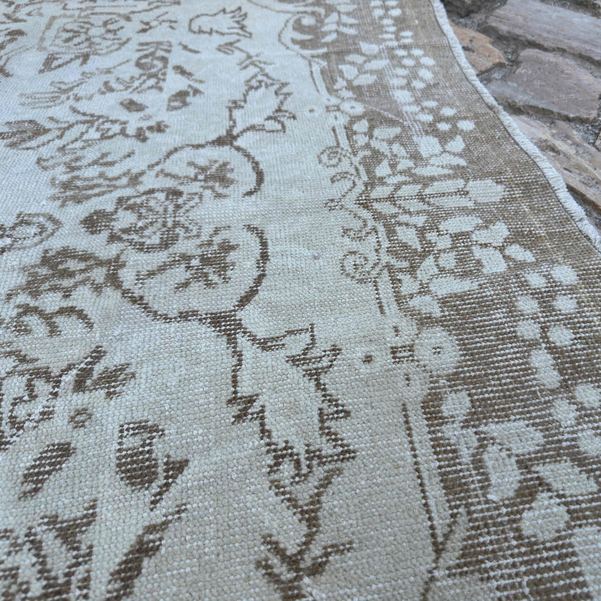 Close-up of the beige vintage Turkish persian rug showing neutral details, hand-knotted weave, wool and cotton and low pile.