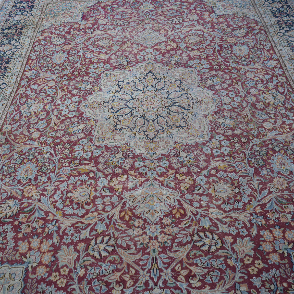 Close-up of the red vintage persian rug showing floral details, hand-knotted weave, wool and cotton and low pile.