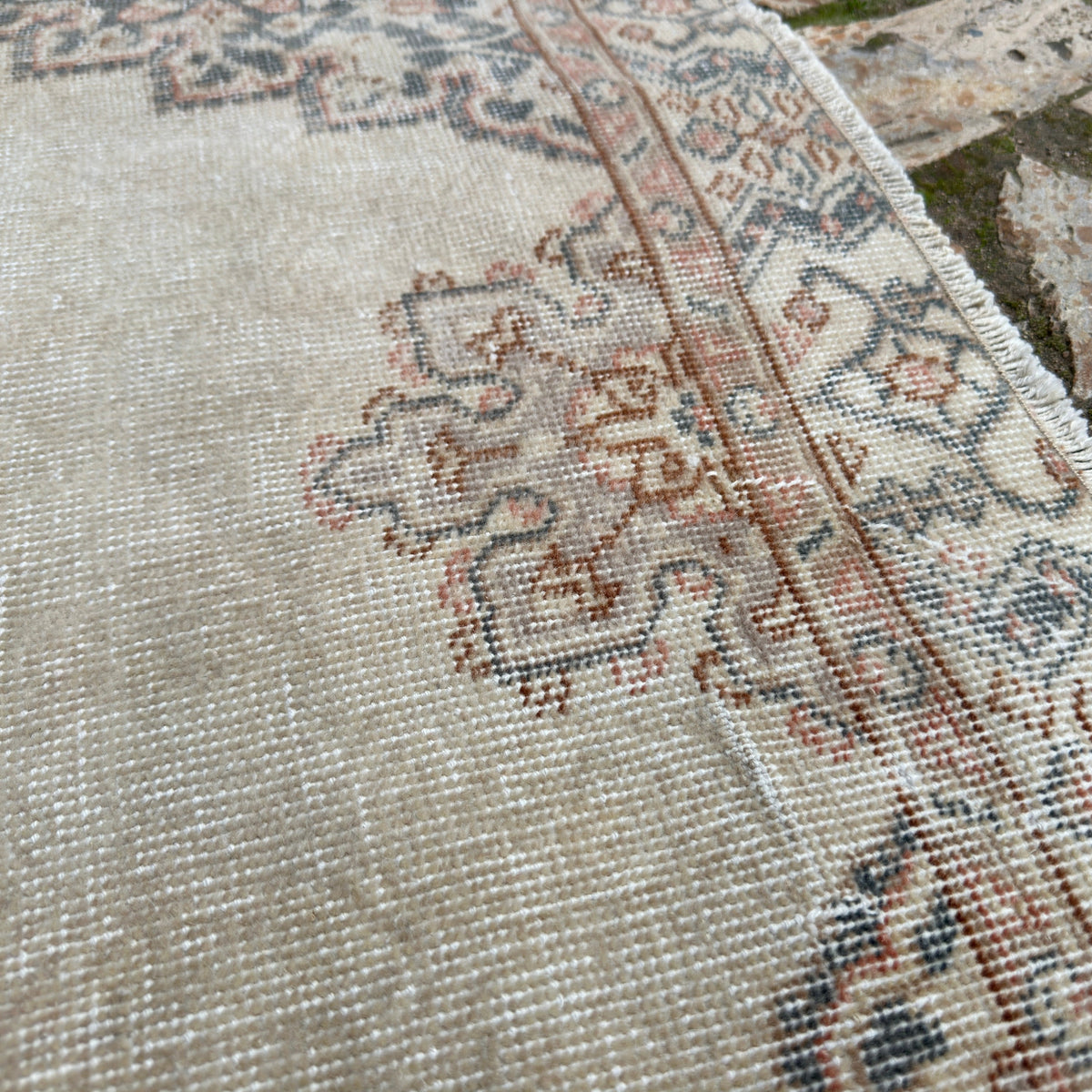 Close-up of the beige vintage Turkish persian style rug showing medallion details, hand-knotted weave, wool and cotton and low pile.
