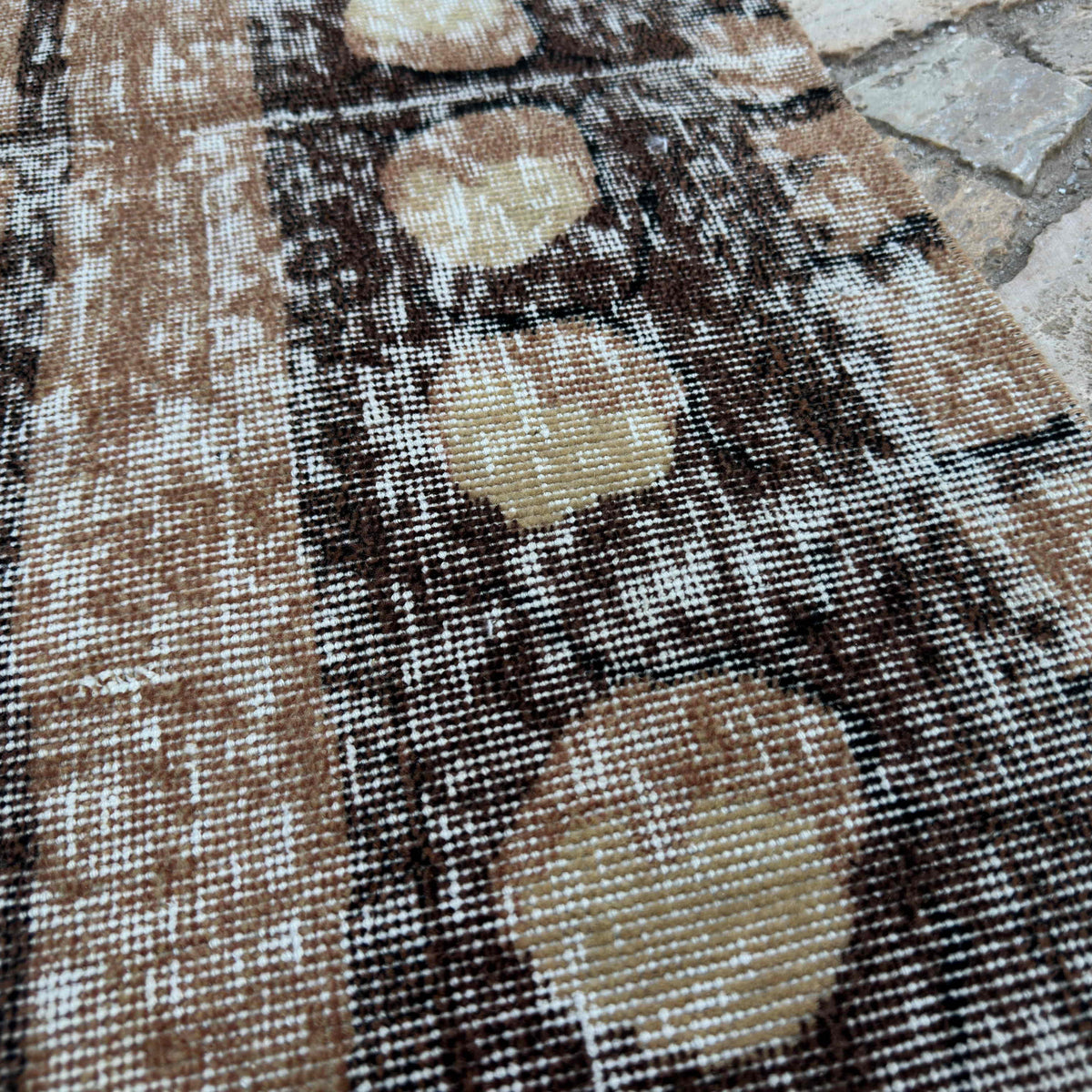 Close-up of the brown vintage Turkish persian style rug showing geometric details, hand-knotted weave, wool and cotton and low pile.