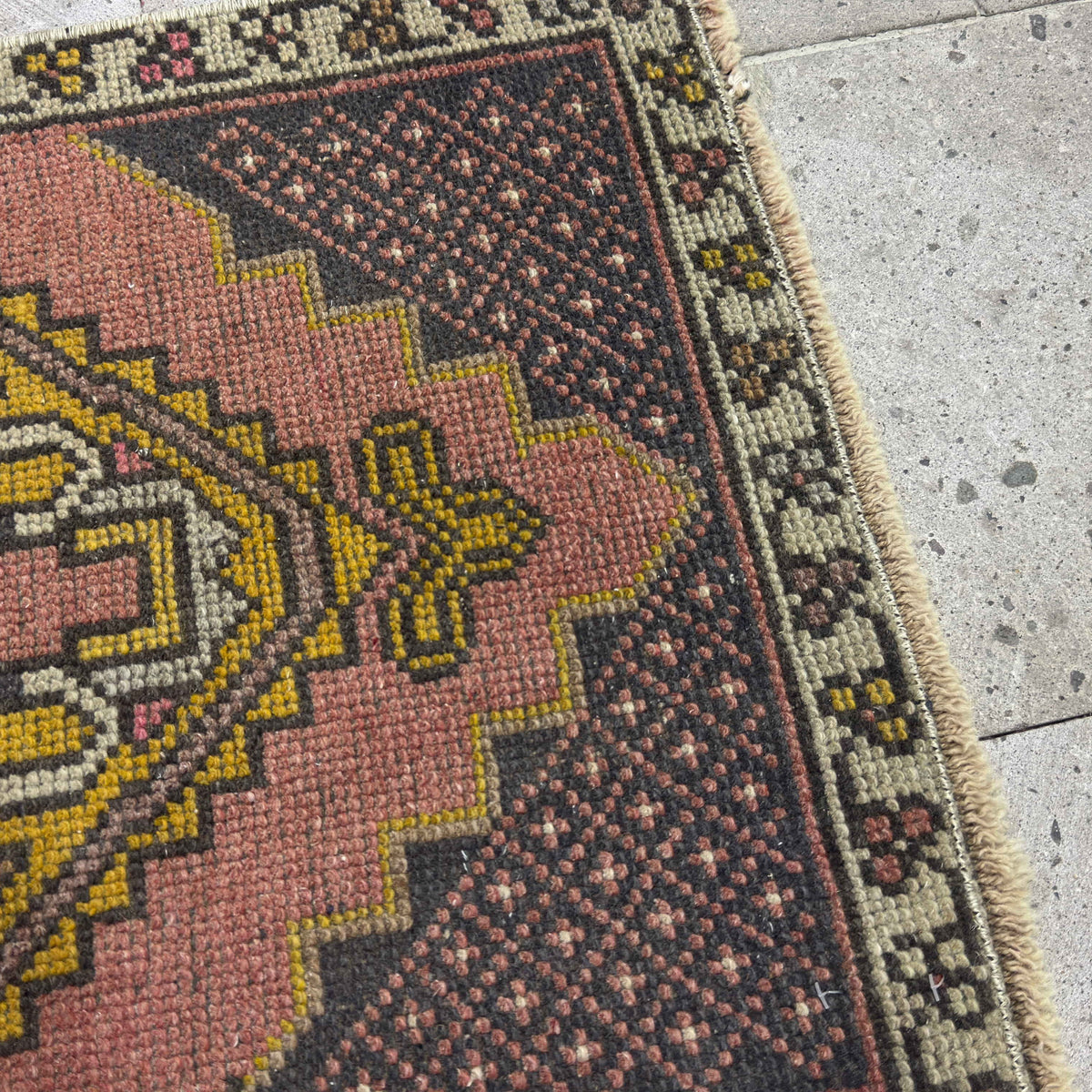 Close-up of the pink vintage Turkish small carpet showing traditional details, hand-knotted weave, wool and cotton and low pile.