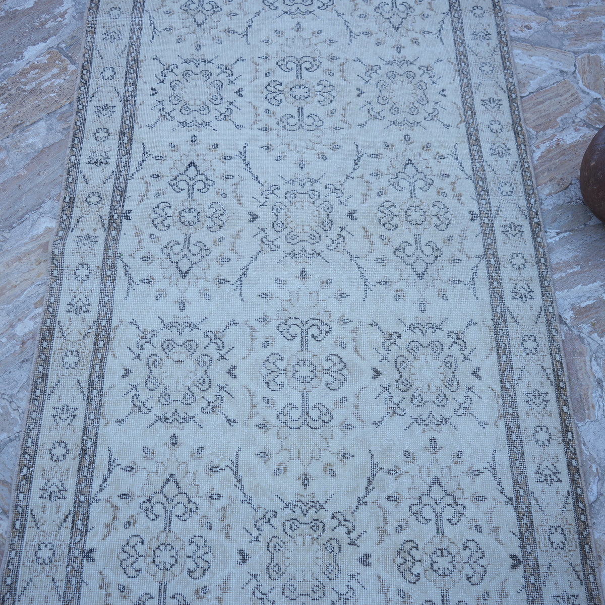 Close-up of the beige vintage Turkish traditional rug showing traditional details, hand-knotted weave, wool and cotton and low pile.