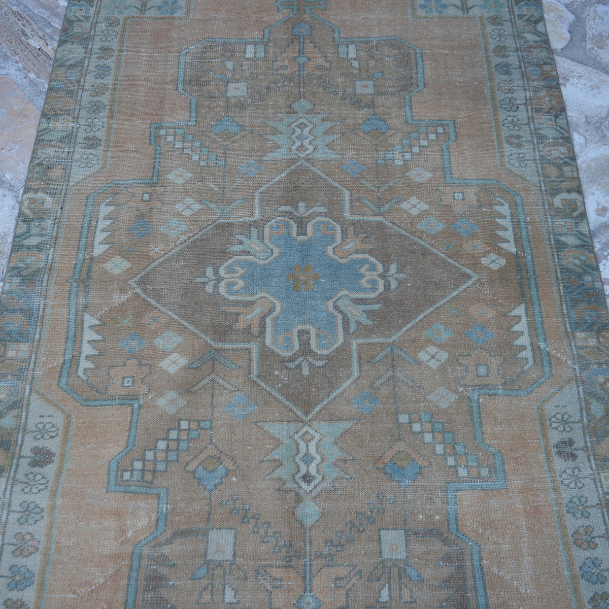 Close-up of the orange vintage Turkish traditional rug showing traditional details, hand-knotted weave, wool and cotton and low pile.