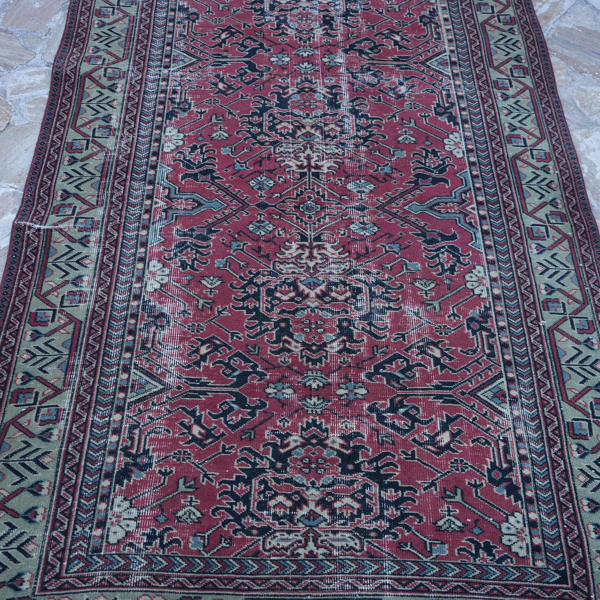 Close-up of the red vintage Turkish traditional rug showing traditional details, hand-knotted weave, wool and cotton and low pile.