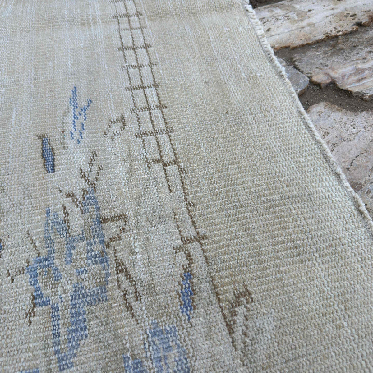 Close-up of the beige vintage Turkish traditional rug showing traditional details, hand-knotted weave, wool and cotton and low pile.