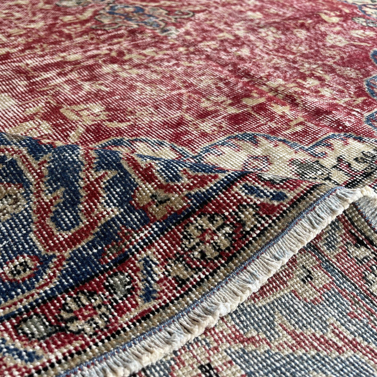 Close-up of the red vintage Turkish traditional rug showing medallion details, hand-knotted weave, wool and cotton and low pile.