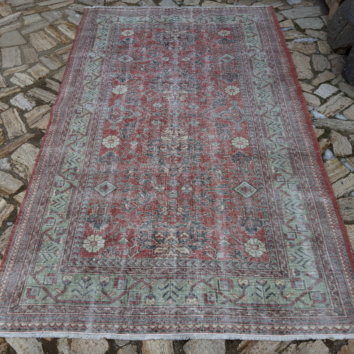 Red 5' x 8' vintage Turkish traditonal rug in wool and cotton, shown on the floor.