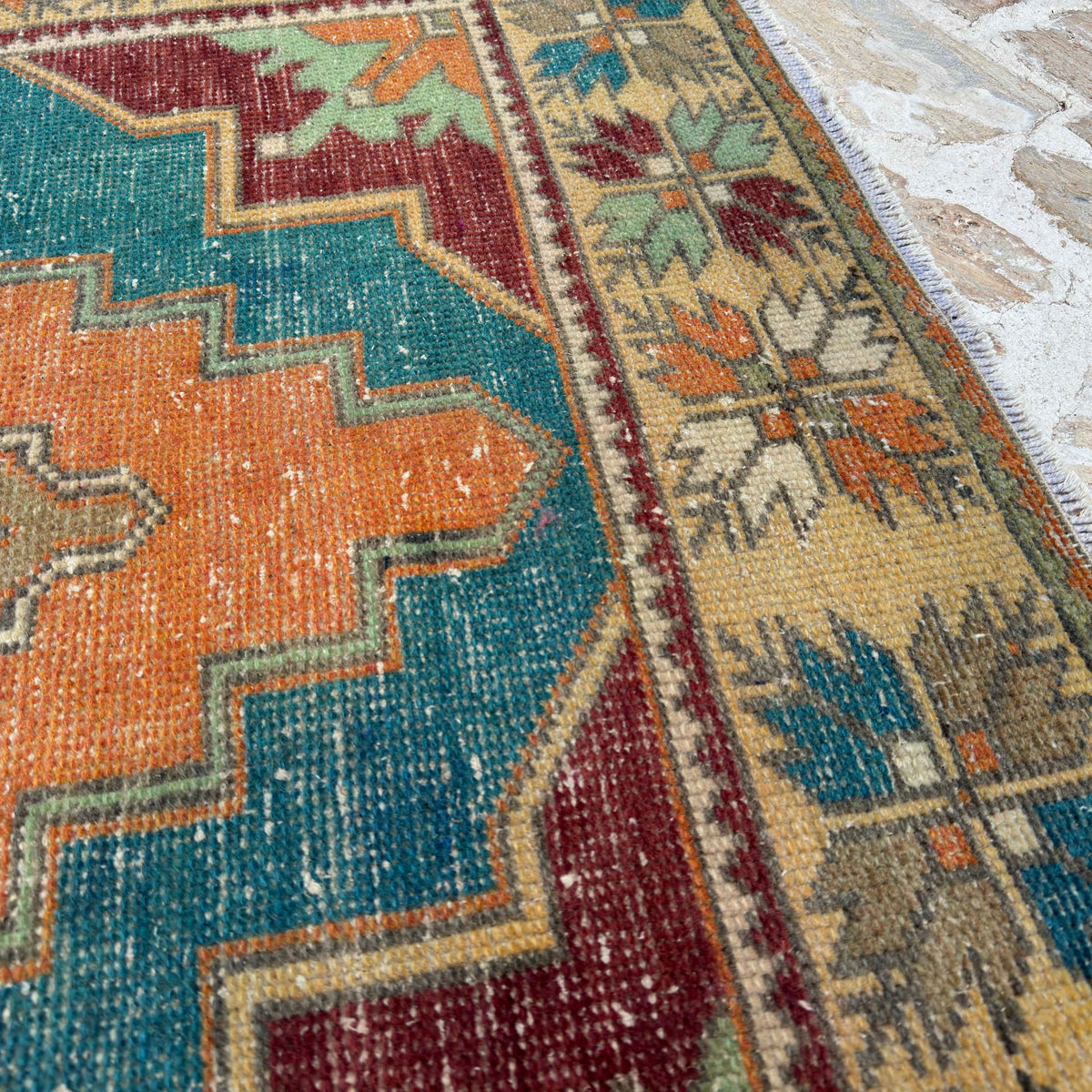 Close-up of the orange vintage turkish carpet showing medallion details, hand-knotted weave, wool and cotton and low pile.