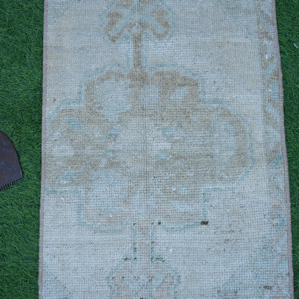 Close-up of the beige vintage turkish rug showing neutral details, hand-knotted weave, wool and cotton and low pile.