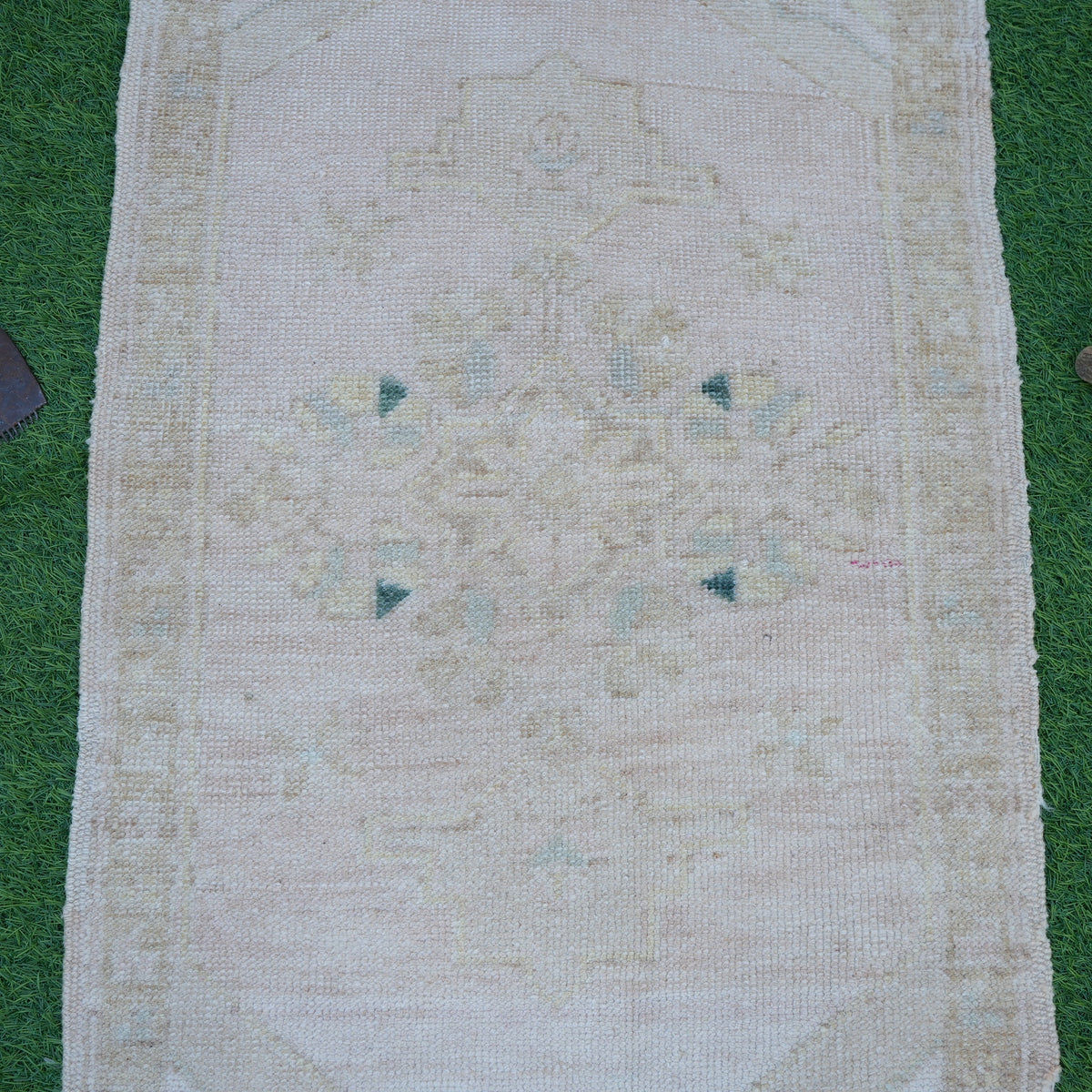 Close-up of the beige vintage turkish rug showing neutral details, hand-knotted weave, wool and cotton and low pile.