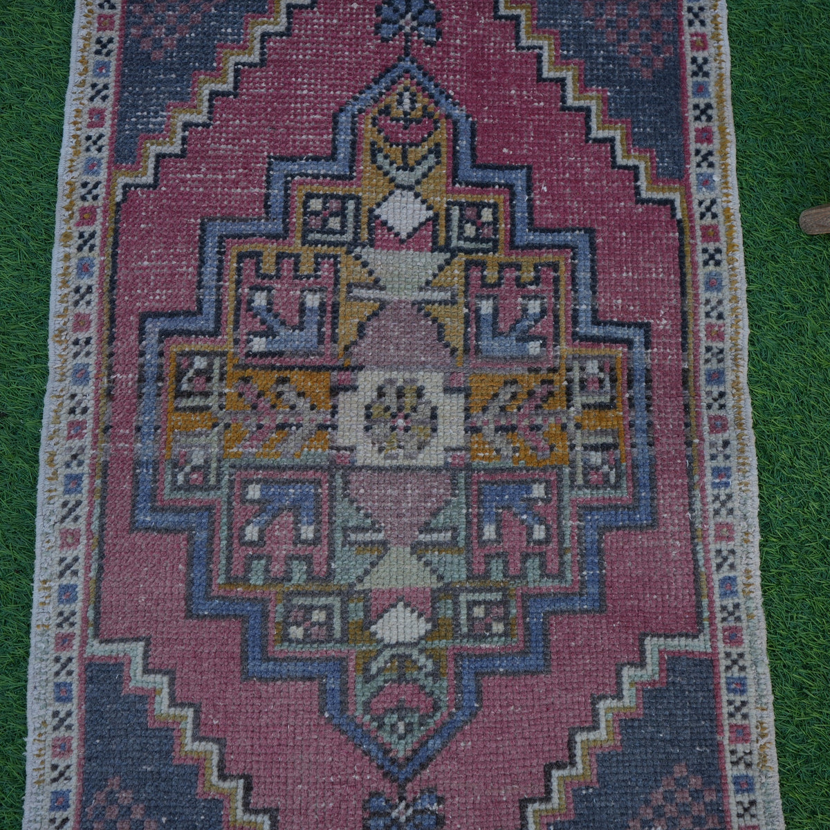 Close-up of the pale red vintage turkish rug showing traditional details, hand-knotted weave, wool and cotton and low pile.