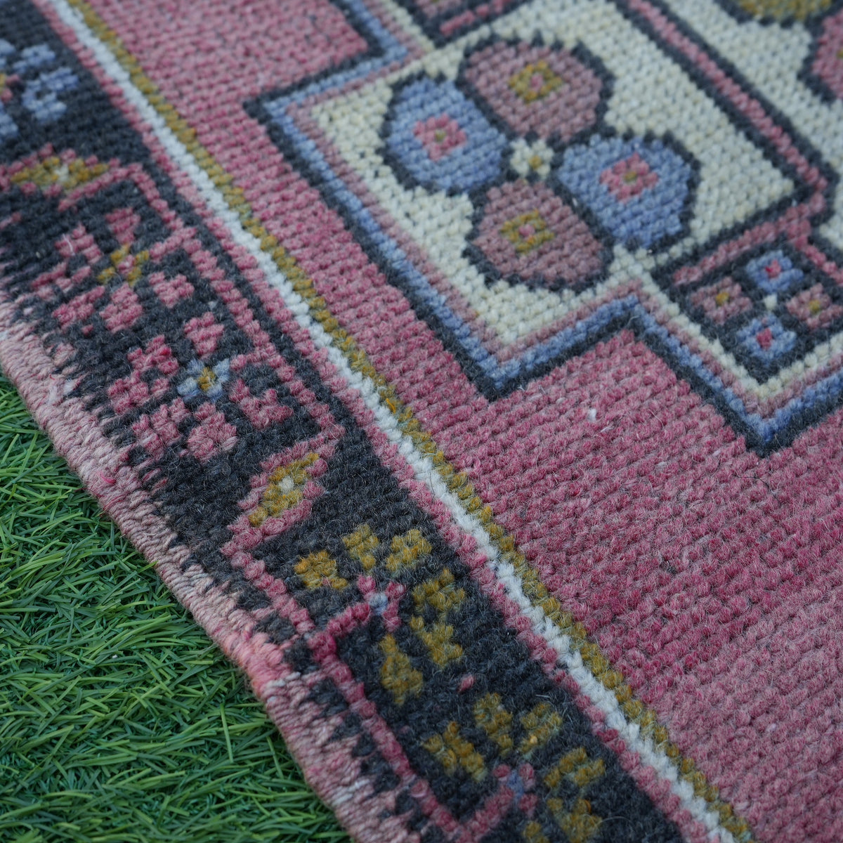 Pink 2' x 3' vintage turkish rug in wool and cotton, shown on the floor.