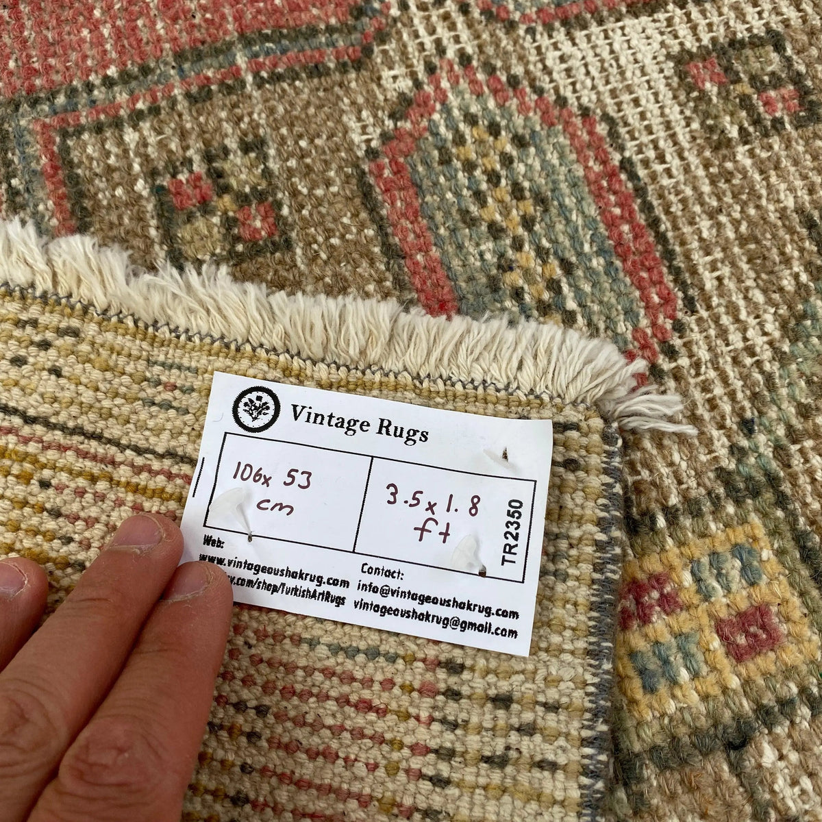 Close-up of the pink vintage turkish rug showing geometric details, hand-knotted weave, wool and cotton and low pile.