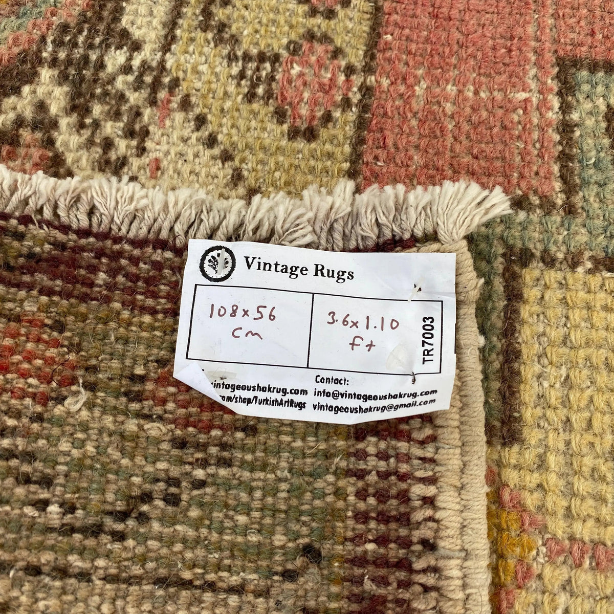 Close-up of the pink vintage turkish rug showing geometric details, hand-knotted weave, wool and cotton and low pile.