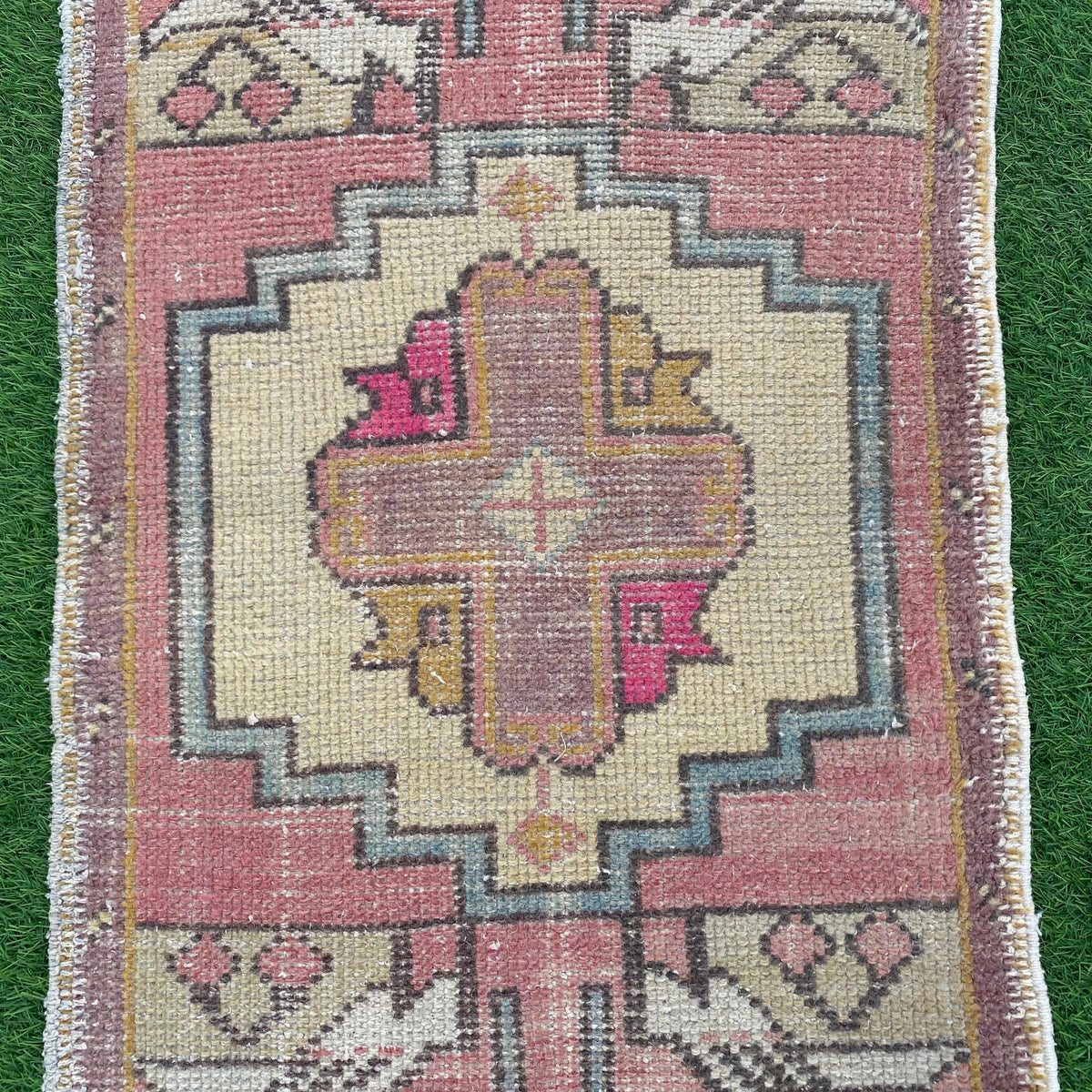 1970s pink vintage turkish rug with geometric design, hand-knotted weave and low pile.