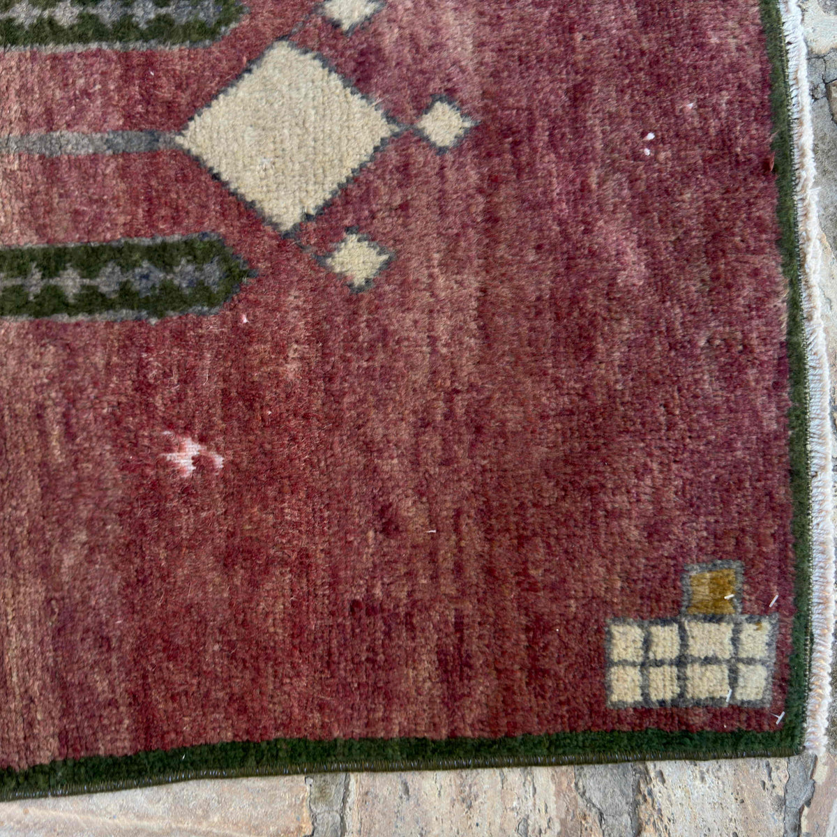 Close-up of the red vintage turkish rug showing traditional details, hand-knotted weave, wool and cotton and low pile.