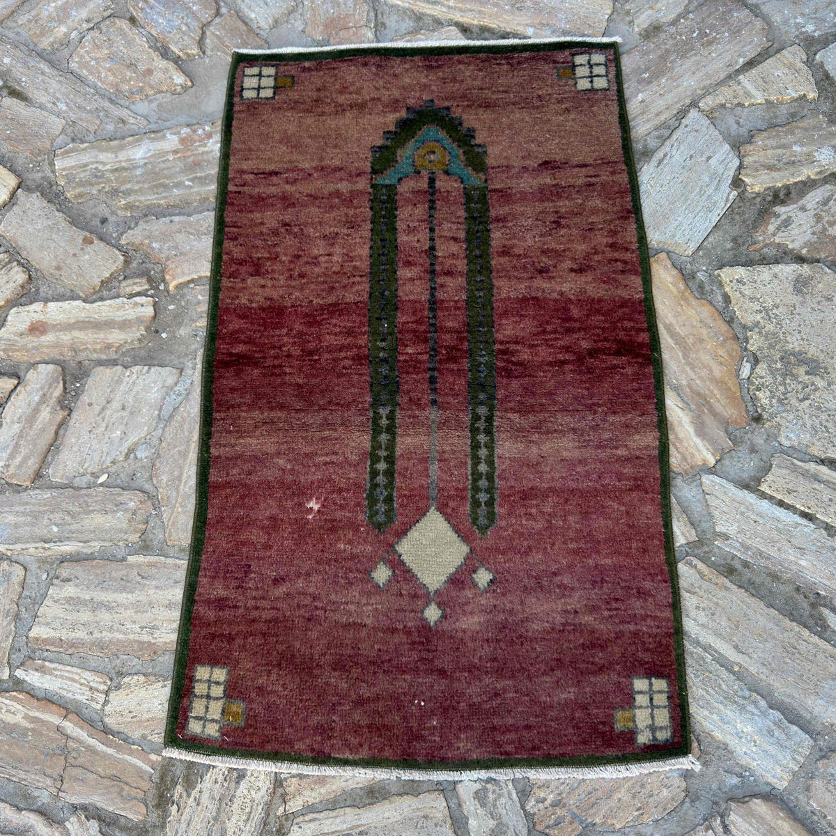 Red 2' x 4' vintage turkish rug in wool and cotton, shown on the floor.
