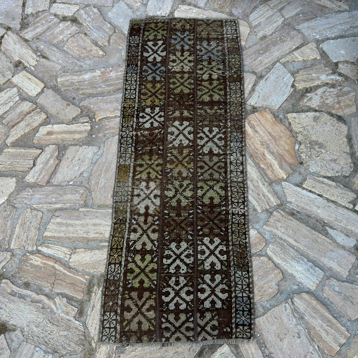 Brown 2' x 5' vintage turkish rug in wool and cotton, shown on the floor.