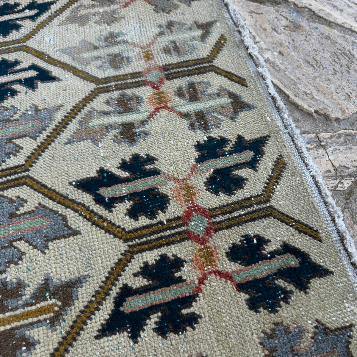 Close-up of the beige vintage turkish rug showing floral details, hand-knotted weave, wool and cotton and low pile.